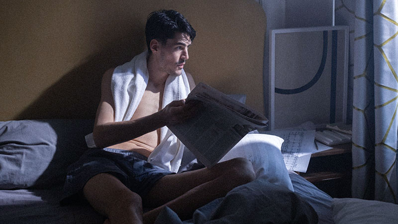 ベッドの上で朝の身支度をする男性