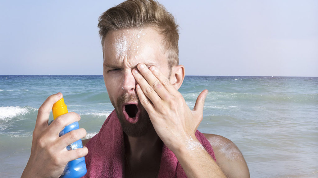 夏のビーチで日焼け止めを塗る男性